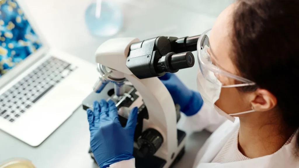 Analyst reading a sample at a laboratory microscope